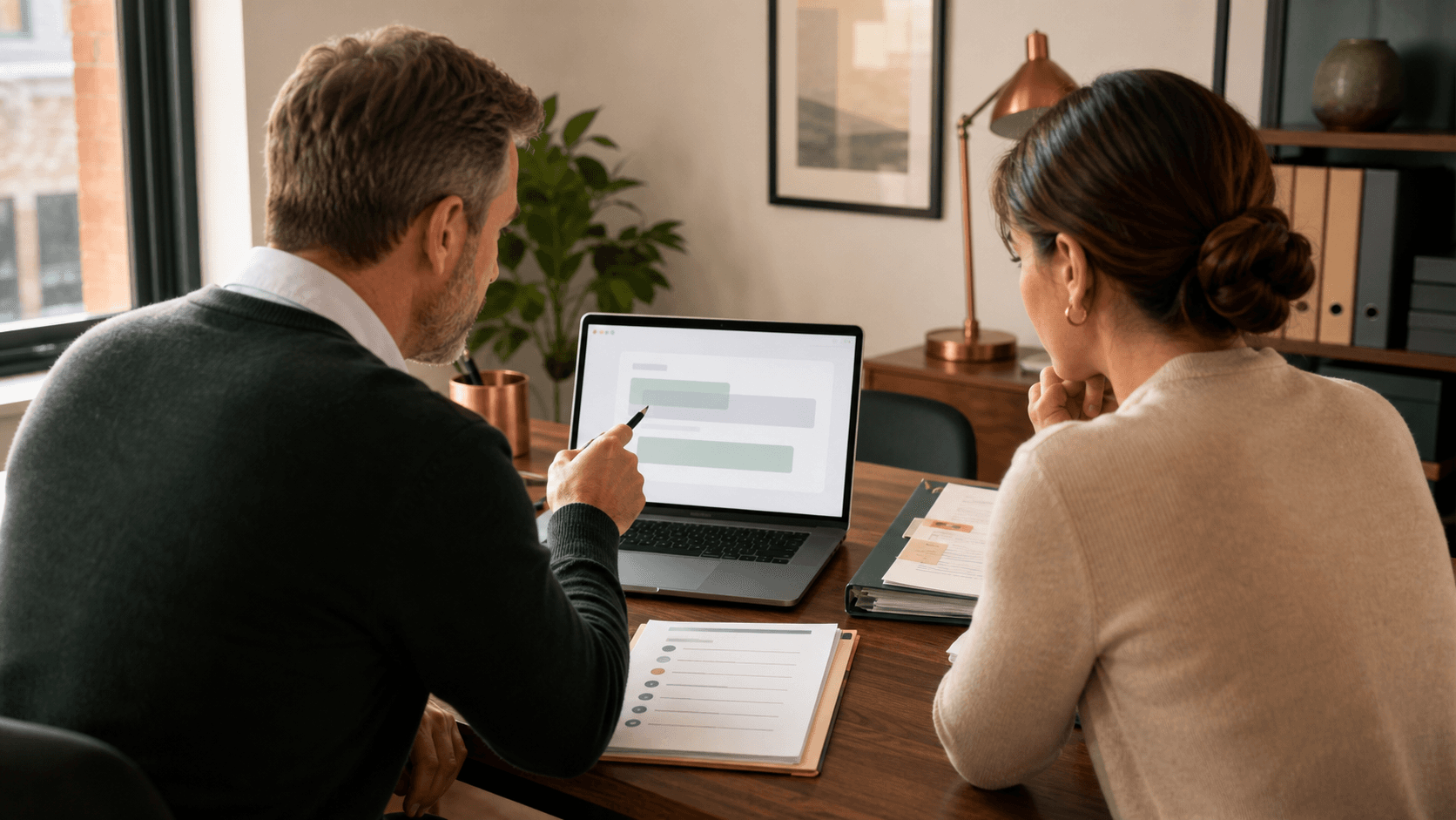 A manager and employee review an AI-assisted draft, privacy checklist, and approved source notes beside a laptop in a small office.